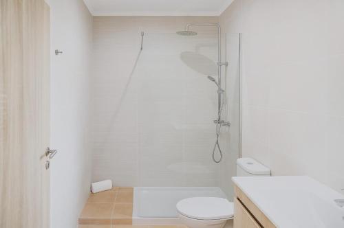 a white bathroom with a shower and a toilet at Fly House Faro in FAO