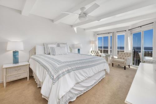 a white bedroom with a bed and a view of the ocean at Beach Club #429 in Saint Simons Island