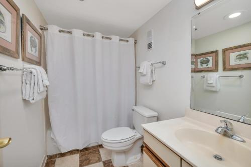 a white bathroom with a toilet and a sink at Beach Club #429 in Saint Simons Island