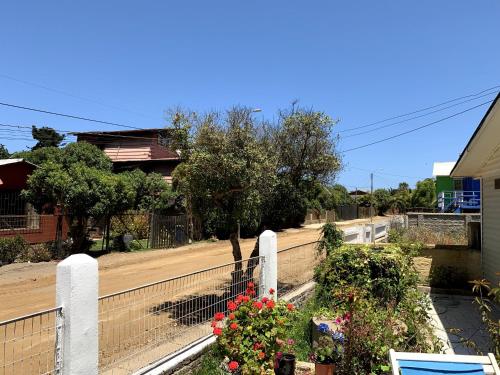 a house with a fence and flowers on a street at Casa familiar cerca de la playa in La Laguna Zapallar