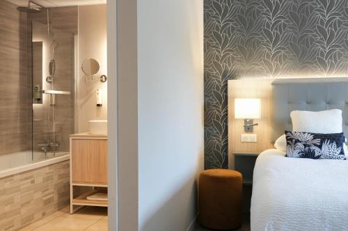 a bedroom with a bed and a bathroom with a shower at Logis Hôtel l'Amandier in Morlaas