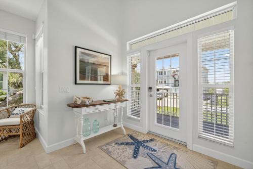 a living room with white walls and windows and a table at Sea Oats Oasis in Sanibel