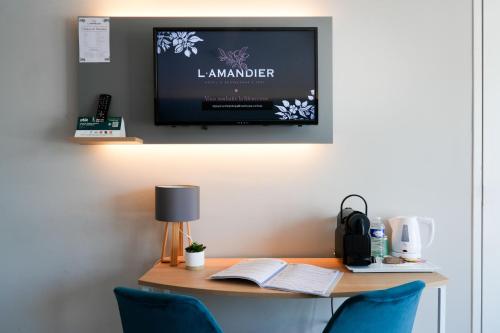 a room with a desk with a tv on the wall at Logis Hôtel l'Amandier in Morlaas