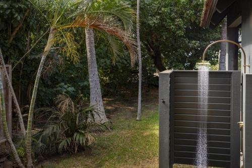 a water fountain outside of a house with a palm tree at Hui Pu in Waikoloa