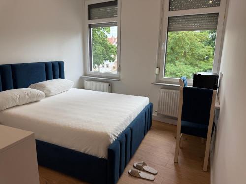 a bedroom with a bed and a desk and two windows at Hotel &Restaurant Meteora in Glauchau