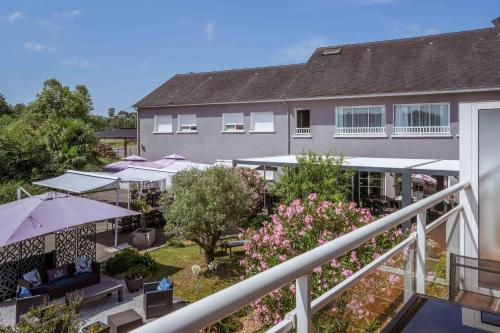 an aerial view of a building with tables and umbrellas at Logis Hôtel l'Amandier in Morlaas