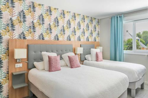 two beds with pink pillows in a bedroom at Logis Hôtel l'Amandier in Morlaas