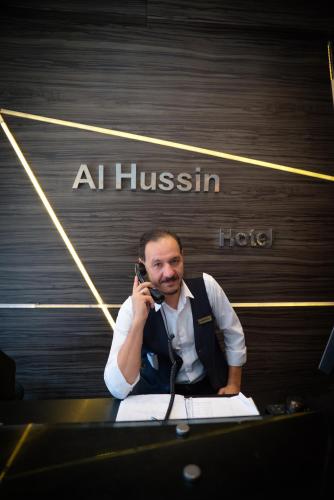 a man talking on a cell phone in front of a hotel at فندق الحسين السياحي in Asyut