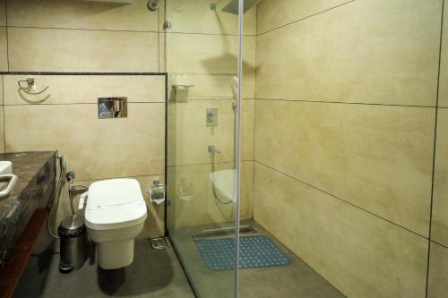 a bathroom with a toilet and a glass shower at Royal Plaza Suites by RAK Rooms, Mangaluru in Mangalore