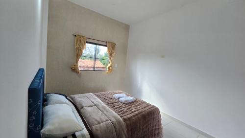 a bedroom with a bed with a blanket and a window at JG&A Home in Itauguá