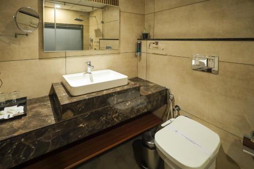 a bathroom with a sink and a toilet at Royal Plaza Suites by RAK Rooms, Mangaluru in Mangalore