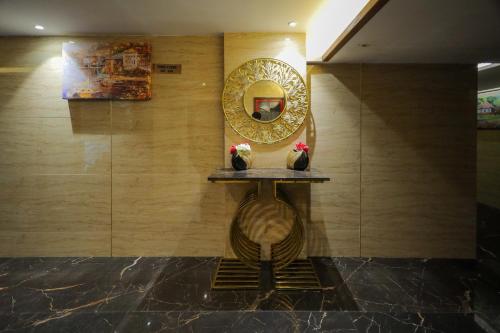 a mirror on a wall with two vases on a shelf at Royal Plaza Suites by RAK Rooms, Mangaluru in Mangalore