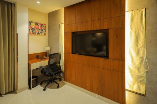a room with a desk and a television on a wall at Royal Plaza Suites by RAK Rooms, Mangaluru in Mangalore