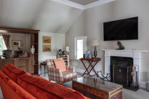 a living room with a red couch and a fireplace at SCHLOSS Roxburghe, part of Destination by Hyatt in Kelso
