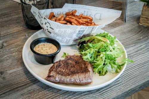 a plate of food with a steak and salad and fries at Logis Hôtel l'Amandier in Morlaas