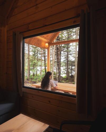 a woman is looking out of a window in a cabin at Huttopia Les Deux Lacs - Laurentides in Mont-Blanc