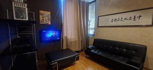a living room with a black leather couch and a television at MARCONI TURIN Loft, studio nei pressi di Porta Nuova in Turin