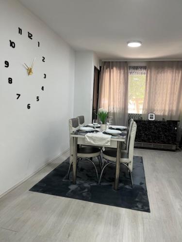 a dining room with a table and chairs and a clock at Apartman u srcu apatina in Apatin