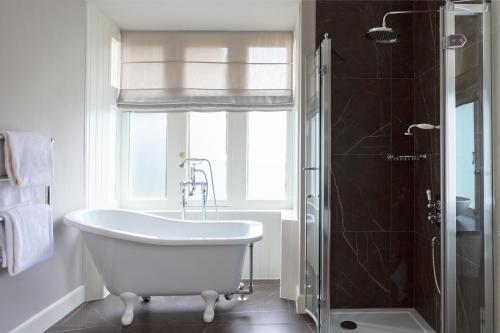 a white bath tub in a bathroom with a window at SCHLOSS Roxburghe, part of Destination by Hyatt in Kelso