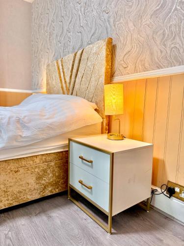 a bedroom with a bed and a nightstand with a lamp at Full Home with Free Parking in Moss Bank, Crumpsall, Manchester in Manchester