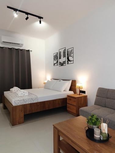 a bedroom with a bed and a couch and a table at Epsilon Premium Studios in Ermoupoli