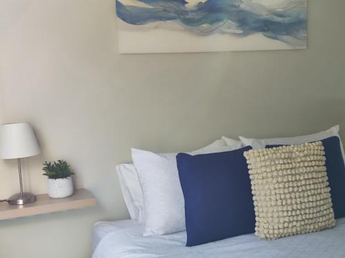 a bed with blue and white pillows and a painting at 505 ,Depto studio NUEVO!, Boutique in Viña del Mar
