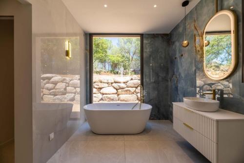 Un baño con dos lavabos y una bañera y una ventana. en Villa Cala Serena, en Zonza