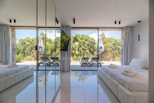 Una sala de estar con dos camas y una pared de cristal. en Villa Cala Serena, en Zonza