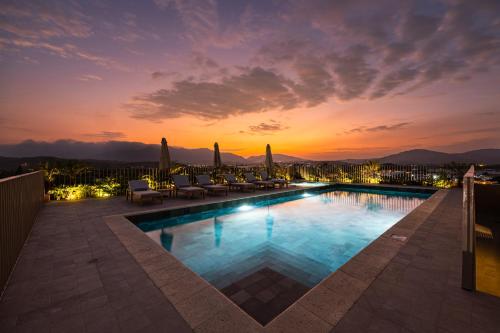 a pool with chairs and a sunset in the background at Oro Verde Portoviejo in Portoviejo