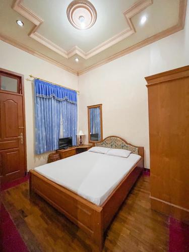 a bedroom with a bed and a desk and a window at Harmadha Villa in Sarangan