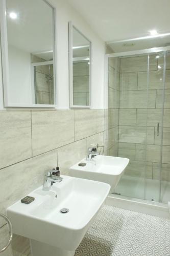 a white bathroom with two sinks and a shower at The Barmouth Bar & Grill in Barmouth