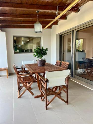 a wooden table with chairs and a potted plant on a patio at Ira Private Villa with Pool in Tragaki