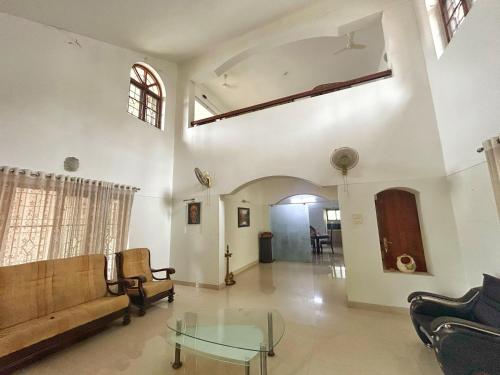 a living room with a couch and a glass table at Citadel Luxury Villa Trivandrum-Just 5 Km to Railway Station & 5 Min to Padmanabha Swamy Temple in Trivandrum