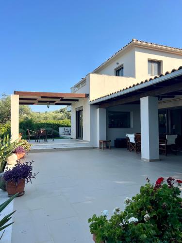 a house with a patio with tables and chairs at Ira Private Villa with Pool in Tragaki