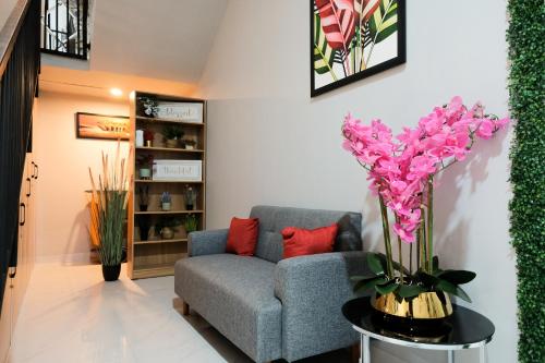 a living room with a couch and a vase with pink flowers at The Tugu Residence in Sawah
