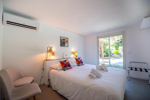 een slaapkamer met een wit bed met een stoel en een raam bij Villa Joia 2 vue mer 7 chambres in Saint-Tropez