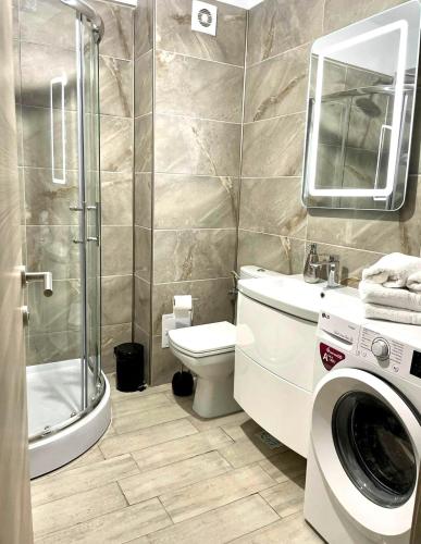 a bathroom with a shower toilet and a washing machine at Nik and dom Alezzi studio in Mamaia Sat/Năvodari