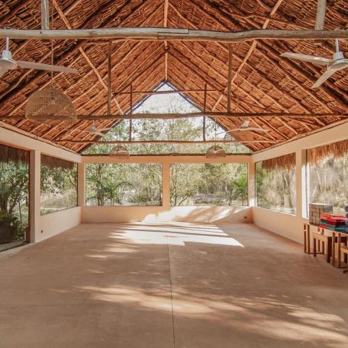 an empty room with a large wooden ceiling with windows at Hacienda Shambalante in Izamal