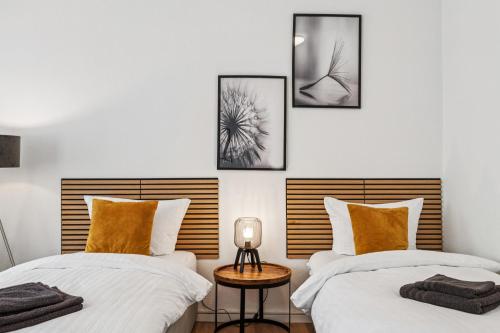 two beds in a room with three pictures on the wall at Comfort Family & Business Apartment in Neunkirchen - 2 SZ - bis zu 5 Pers - Balkon - Badewanne - WLAN 250 Mbit - Parkplatz - Self-Check-in in Neunkirchen