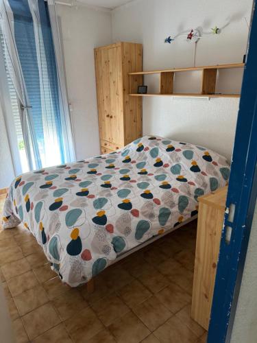 a bedroom with a bed with a colorful comforter at PORT et PLAGE in Le Barcarès