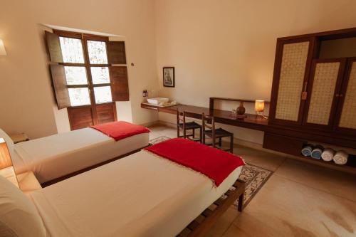 a bedroom with two beds and a desk and a window at Hacienda Shambalante in Izamal