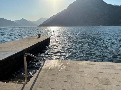 a dock on a lake with mountains in the background at BASTADUR rooms in Kotor