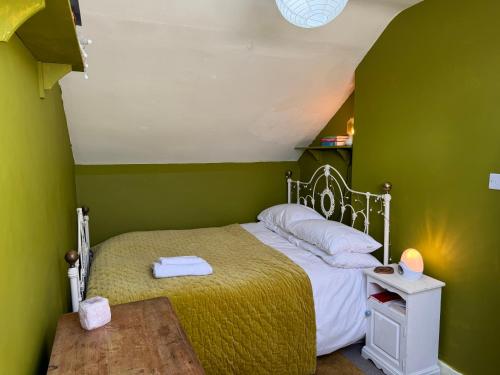 1 dormitorio con paredes verdes, 1 cama y 1 mesa en 8b The Bookcase, en Dawlish