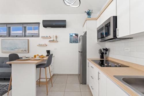 a kitchen with white cabinets and a small island with a table at Villas at Chalet De Buye in Cabo Rojo