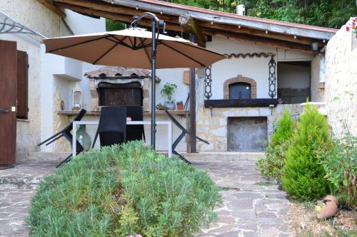 a table with an umbrella in front of a house at CASA VACANZE - LA CASINA DI LALLA - Greccio in Greccio