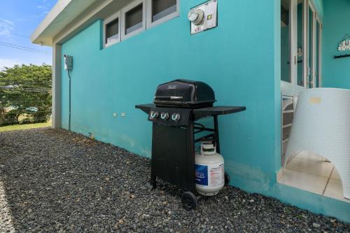 a grill sitting outside of a blue house at Villas at Chalet De Buye in Cabo Rojo