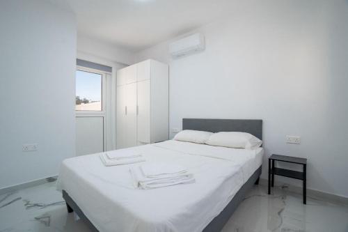 Un dormitorio blanco con una cama grande y una ventana. en Nerina Luxury Villa 01, en Pafos