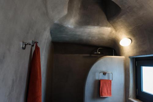 a bathroom with a toilet and a red towel at Alba Superior suite in Emporio Santorini