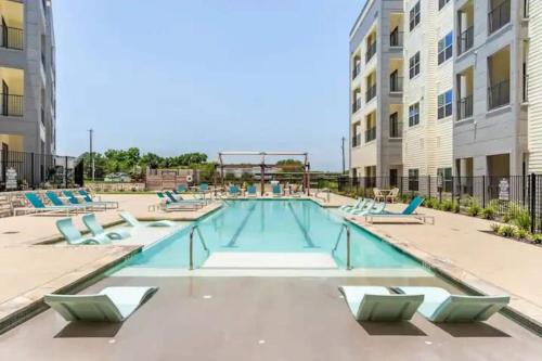 a swimming pool with lounge chairs in a building at Modern 2br Pet-friendly Wd Pool&gym Utsa in San Antonio