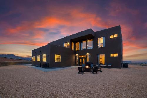 a black house in the desert with a sunset at The Highlander - Luxe Hot Tub Firepit Views in Big Water